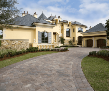 Large two‑story home featuring stone paver driveway and landscaped front yard to illustrate exterior upgrade options