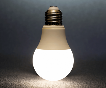 Bright LED light bulb glowing on dark surface to highlight energy‑efficient lighting for homeowners.
