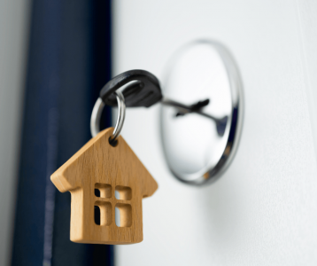 New Homeowner Key Exchange House key turning in door lock with wooden home keychain to illustrate new homeowner security setup